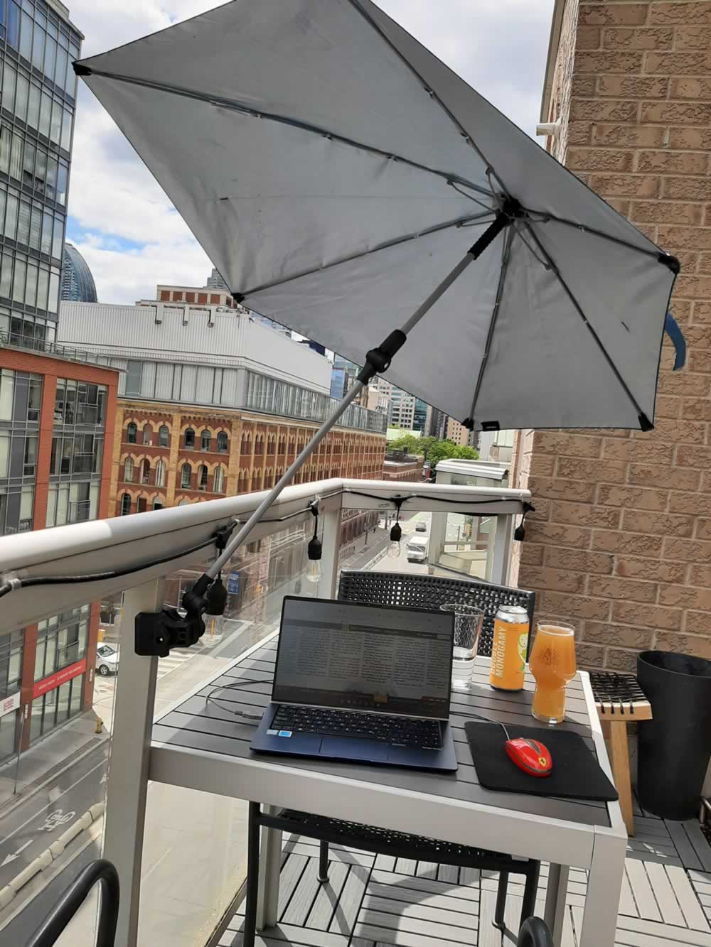 Umbrella on balcony providing shade for working on laptop.