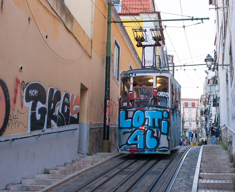 Graffiti drenched Ascensor da Bica riding along Calçada da Bica Pequena in Lisbon.
